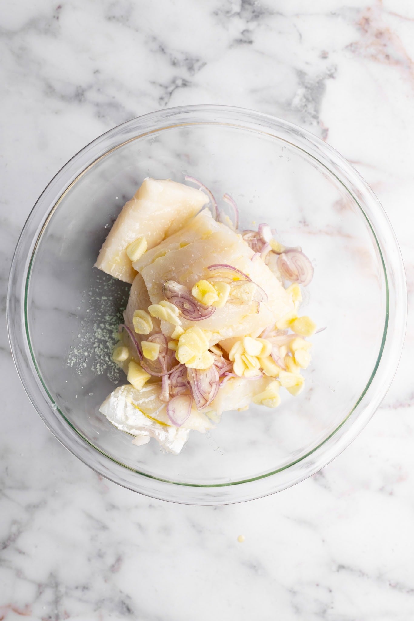 step by step: Seasoning the cod fillets with salt olive oil shallots and garlic.