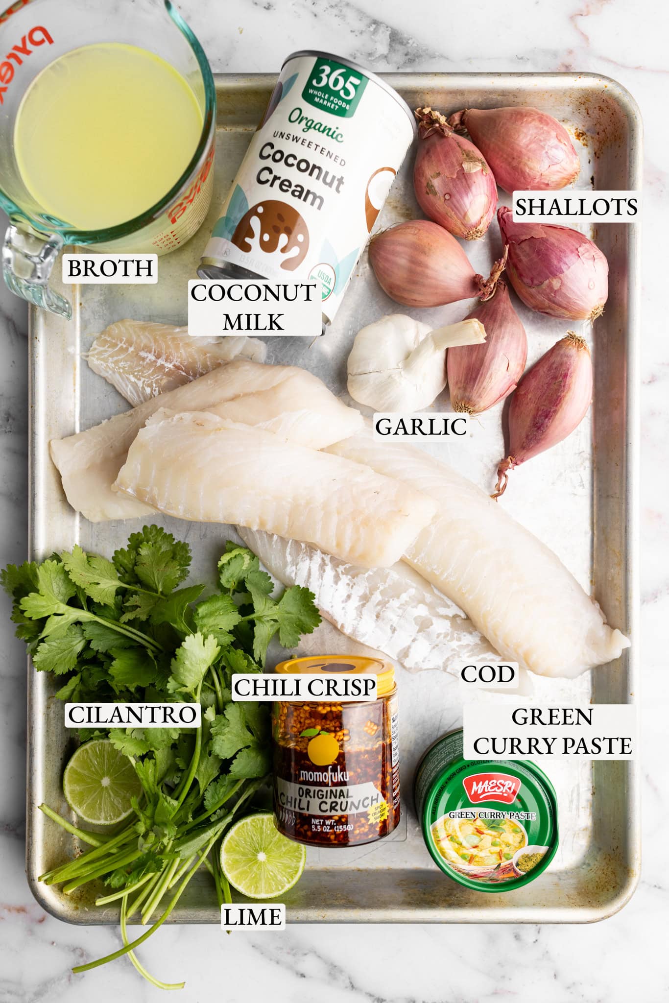 ingredients on a tray: shallots, garlic, coconut milk, green curry paste, cod, chili crisp, cilantro, and lime